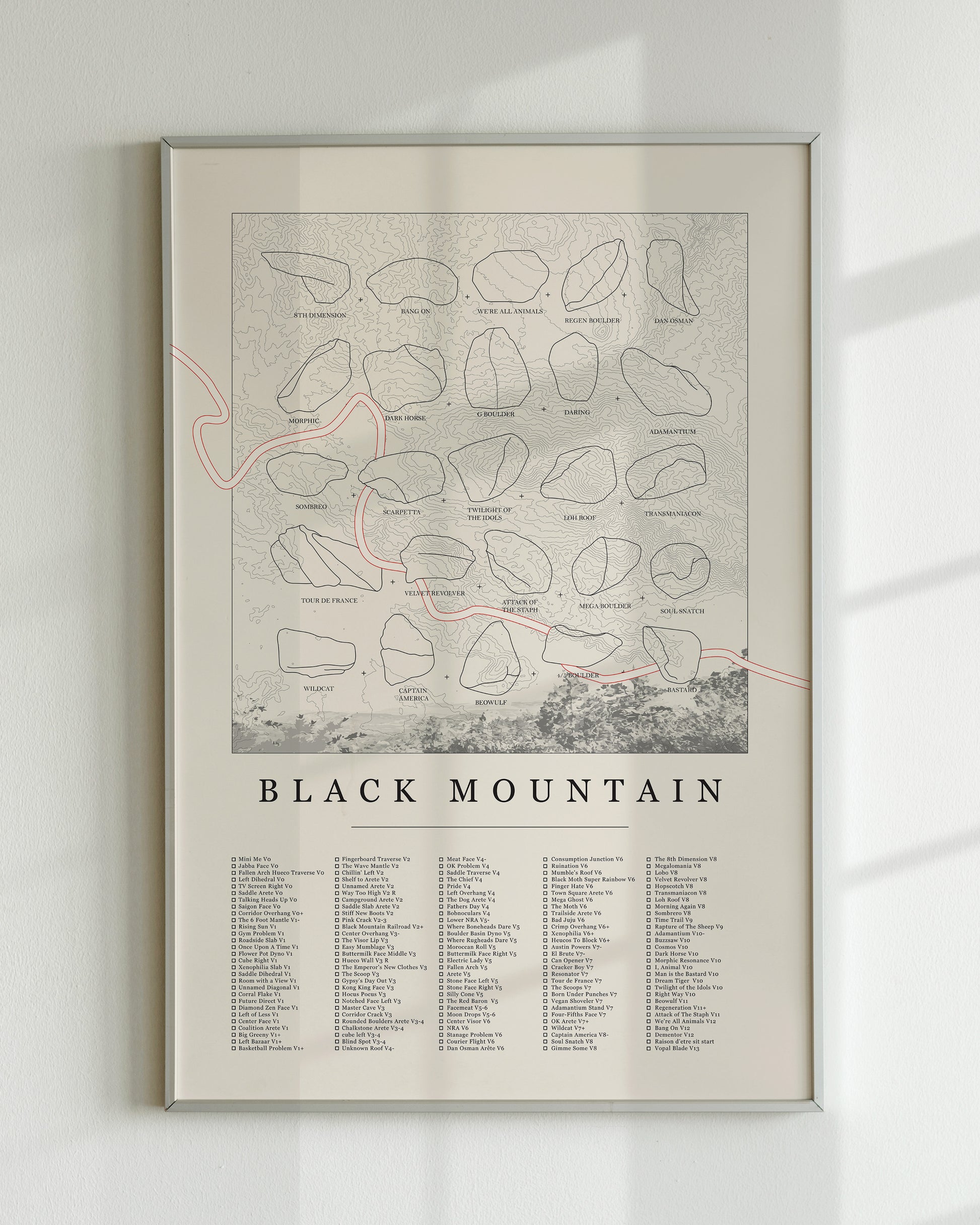 A cream color, standard rock climbing ticklist poster for the Black Mountain rock climbing location in San Jacinto Mountain, California. The design has an overlay of crag topography, nature landscapes, and traced boulders, and a list of bouldering problems at the bottom. Displayed as wall art in a living room.