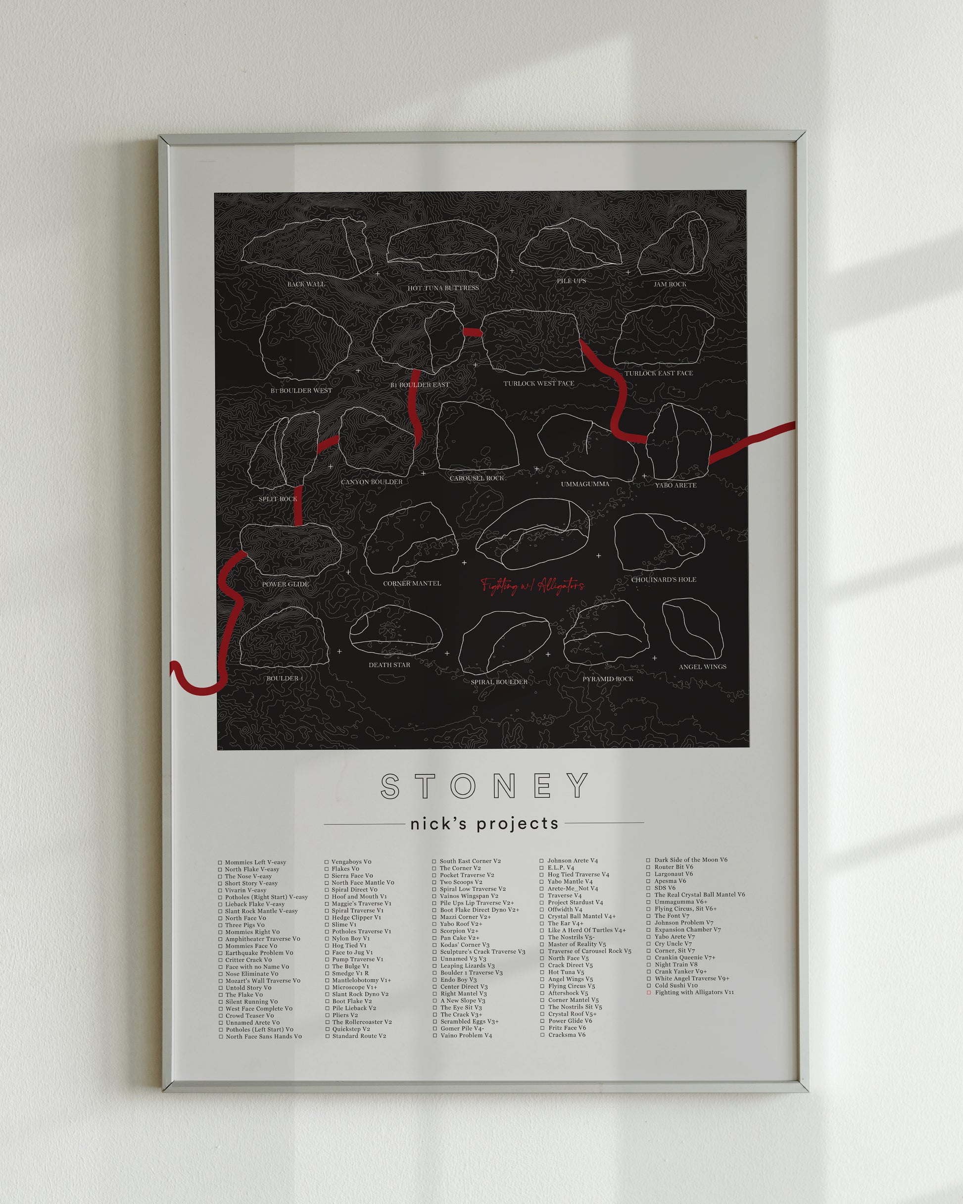 A black color, customized rock climbing ticklist poster for the Buttermilks rock climbing location in Topanga, California. The design has an overlay of crag topography, nature landscapes, and traced boulders, the person's name, and a list of bouldering problems at the bottom. Displayed as wall art in a living room.