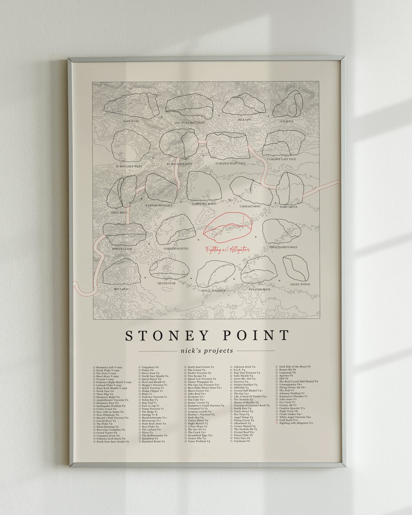 A cream color, customized rock climbing ticklist poster for the Buttermilks rock climbing location in Topanga, California. The design has an overlay of crag topography, nature landscapes, and traced boulders, the person's name, and a list of bouldering problems at the bottom. Displayed as wall art in a living room.