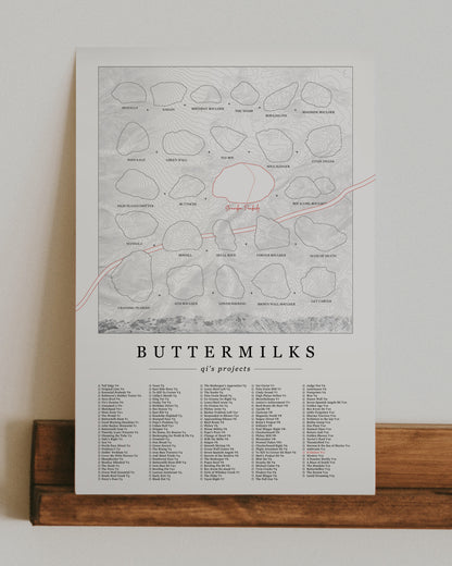 A cream color, customized rock climbing ticklist poster for the Buttermilks rock climbing location in Bishop, California. The design has an overlay of crag topography, nature landscapes, and traced boulders, the person's name, and a list of bouldering problems at the bottom. Displayed as wall art in a living room.
