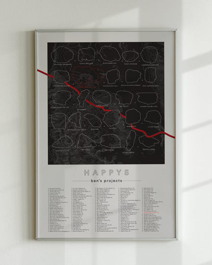 A black color, customized rock climbing ticklist poster for the Happys rock climbing location in Bishop, California. The design has an overlay of crag topography, nature landscapes, and traced boulders, the person's name, and a list of bouldering problems at the bottom. Displayed as wall art in a living room.