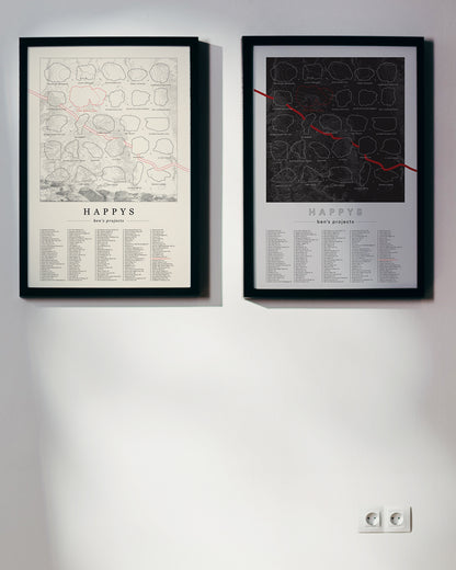 Both black and cream color, customized rock climbing ticklist posters for the Happys rock climbing location in Bishop, California. The design has an overlay of crag topography, nature landscapes, and traced boulders, the person's name, and a list of bouldering problems at the bottom. Displayed as wall art in a living room.