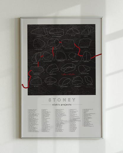 A black color, customized rock climbing ticklist poster for the Buttermilks rock climbing location in Topanga, California. The design has an overlay of crag topography, nature landscapes, and traced boulders, the person's name, and a list of bouldering problems at the bottom. Displayed as wall art in a living room.