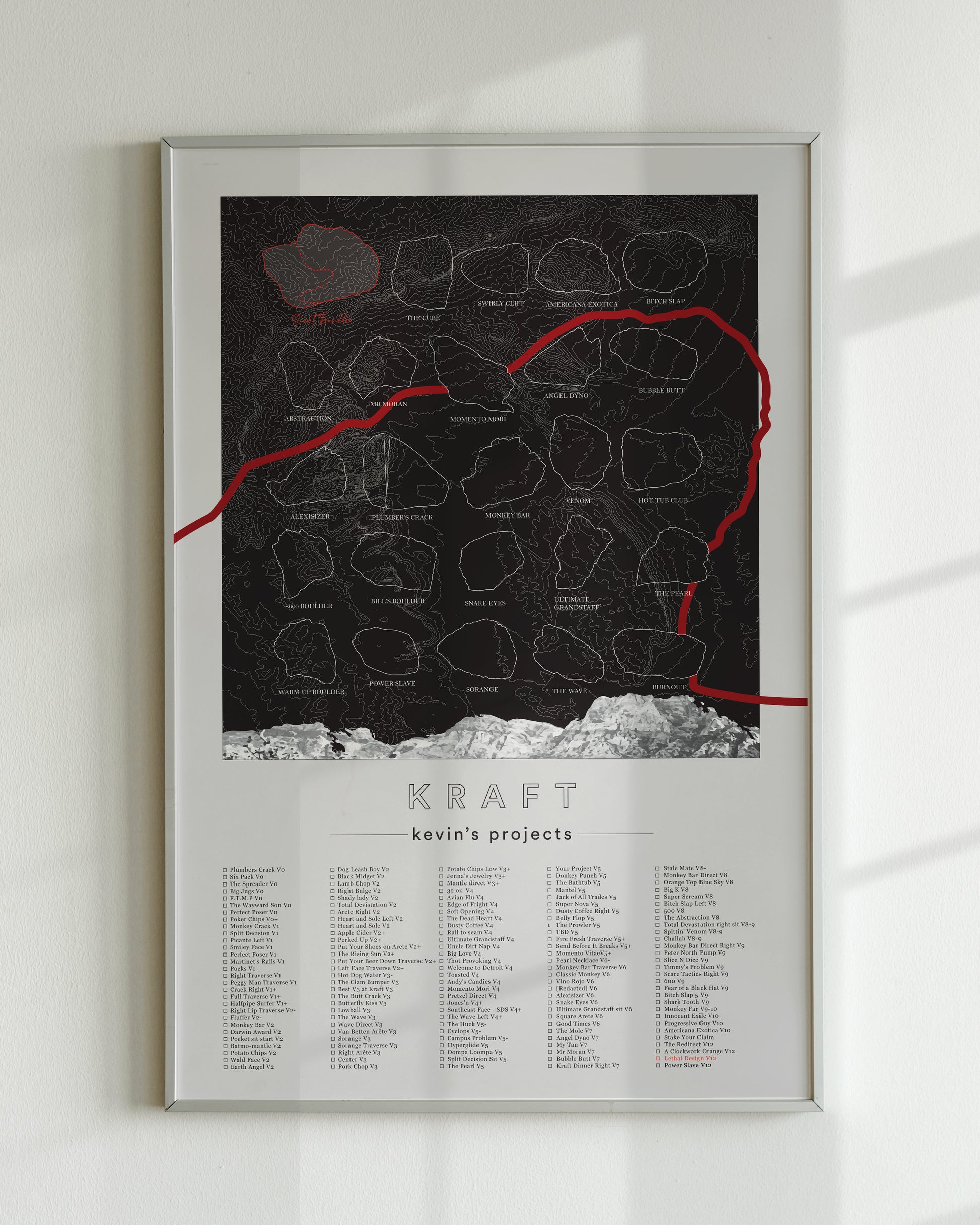 A black color, customized rock climbing ticklist poster for the Kraft rock climbing location at the Red Rocks in Las Vegas, Nevada. The design has an overlay of crag topography, nature landscapes, and traced boulders, the person's name, and a list of bouldering problems at the bottom. Displayed as wall art in a living room.